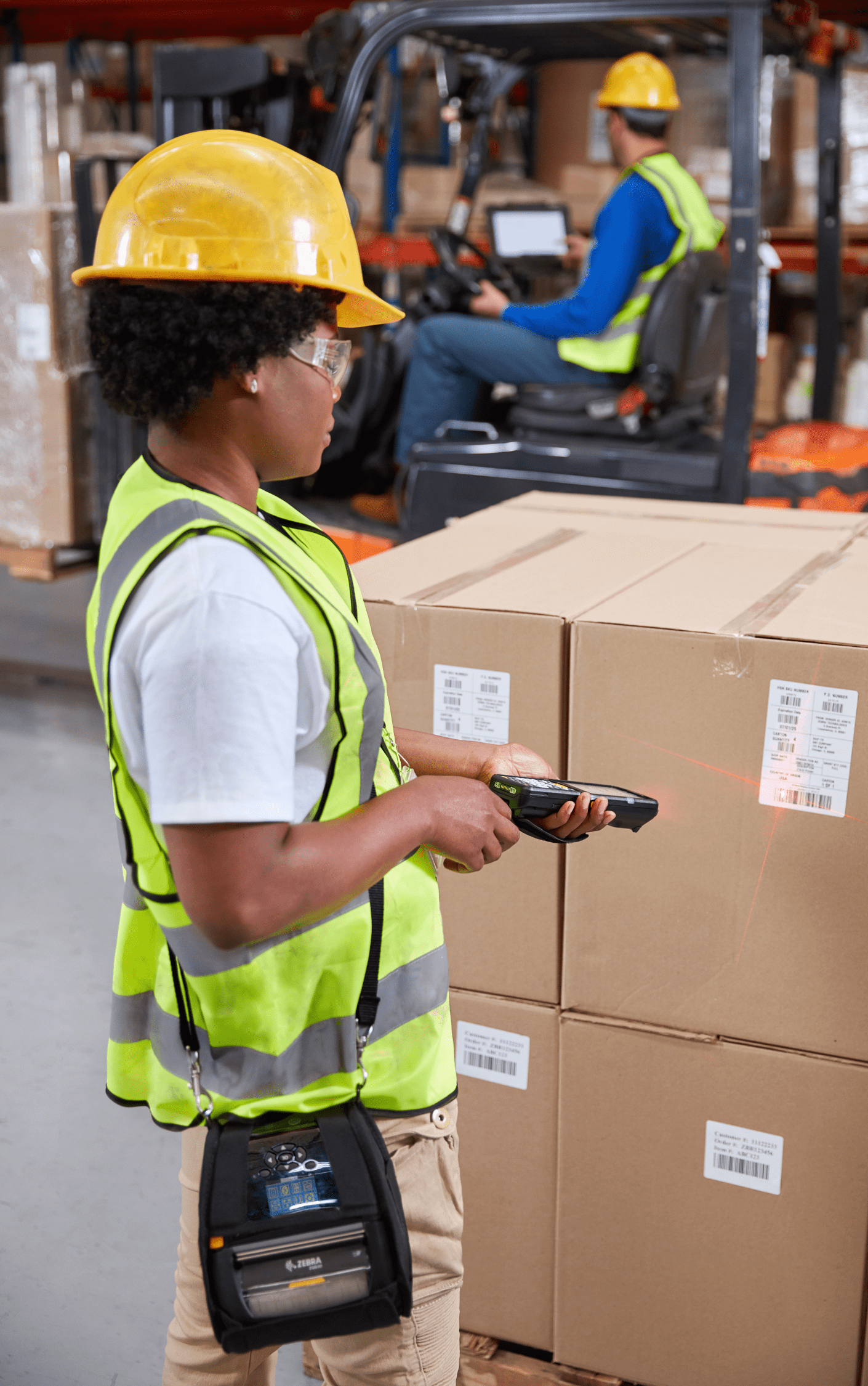 Person with a hand scanner looking over a stack of boxes.